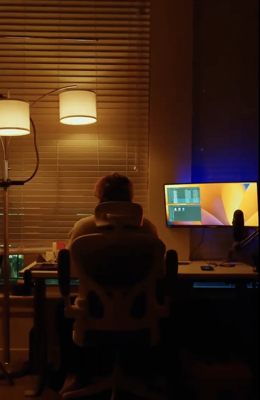 Someone working late at a desk with two monitors